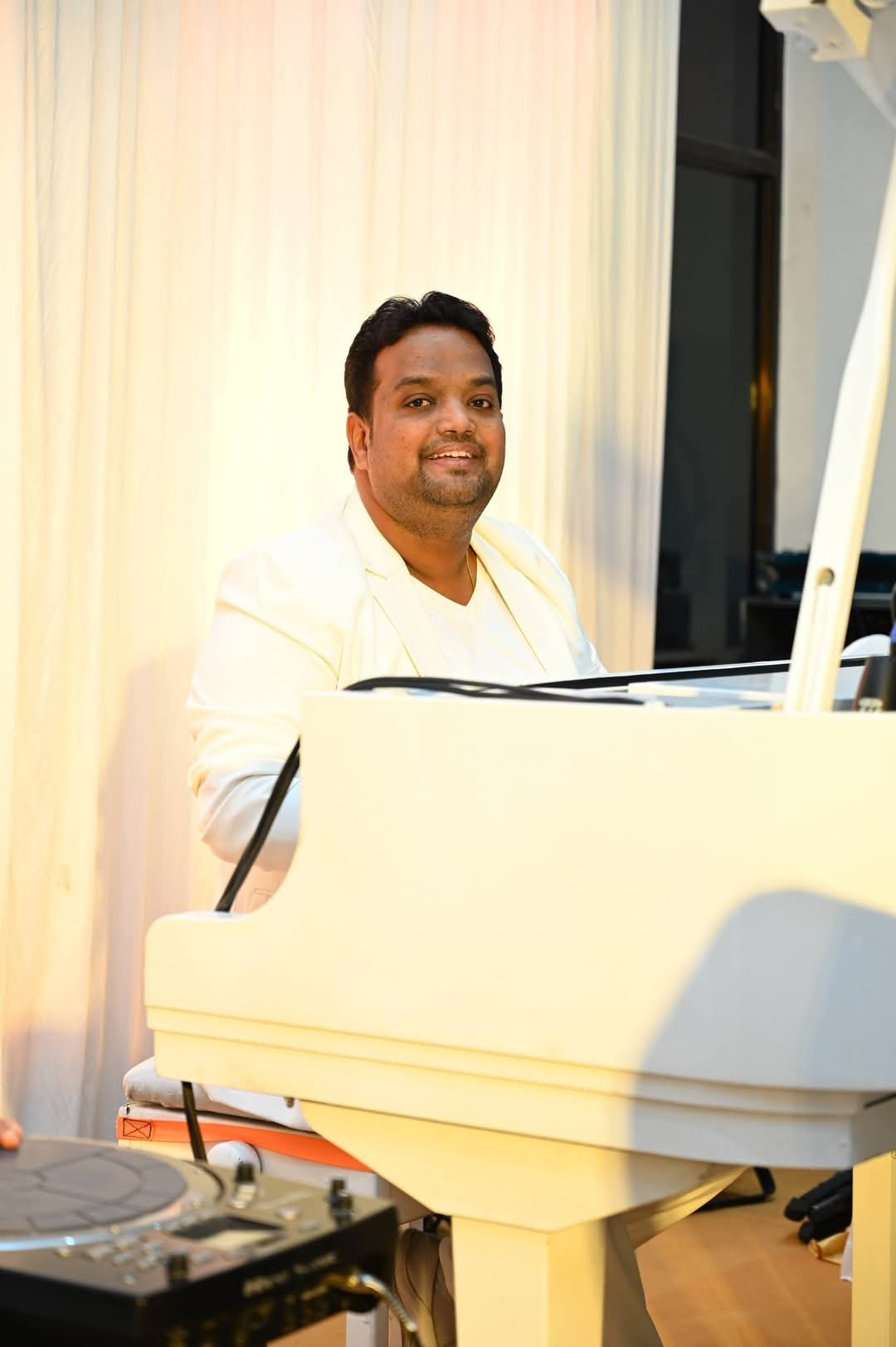 Vaibhav Pewal smiling at the white grand piano