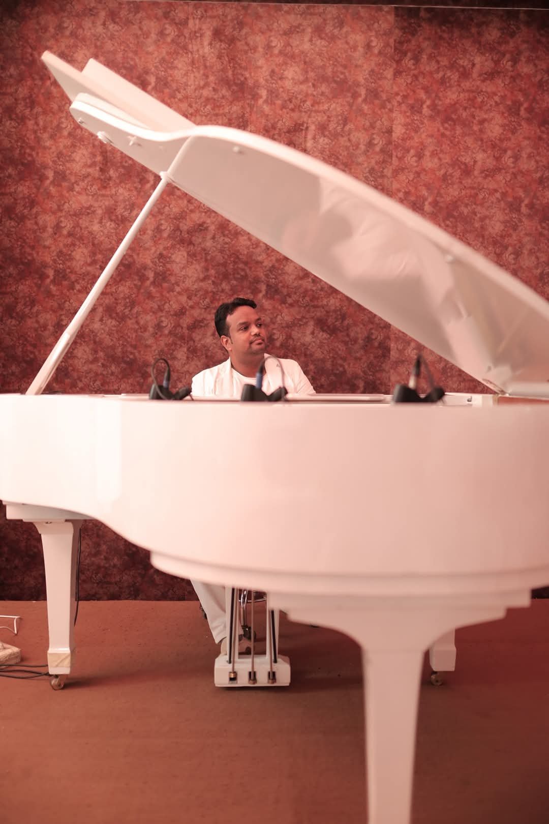 Vaibhav Pewal behind the open white grand piano