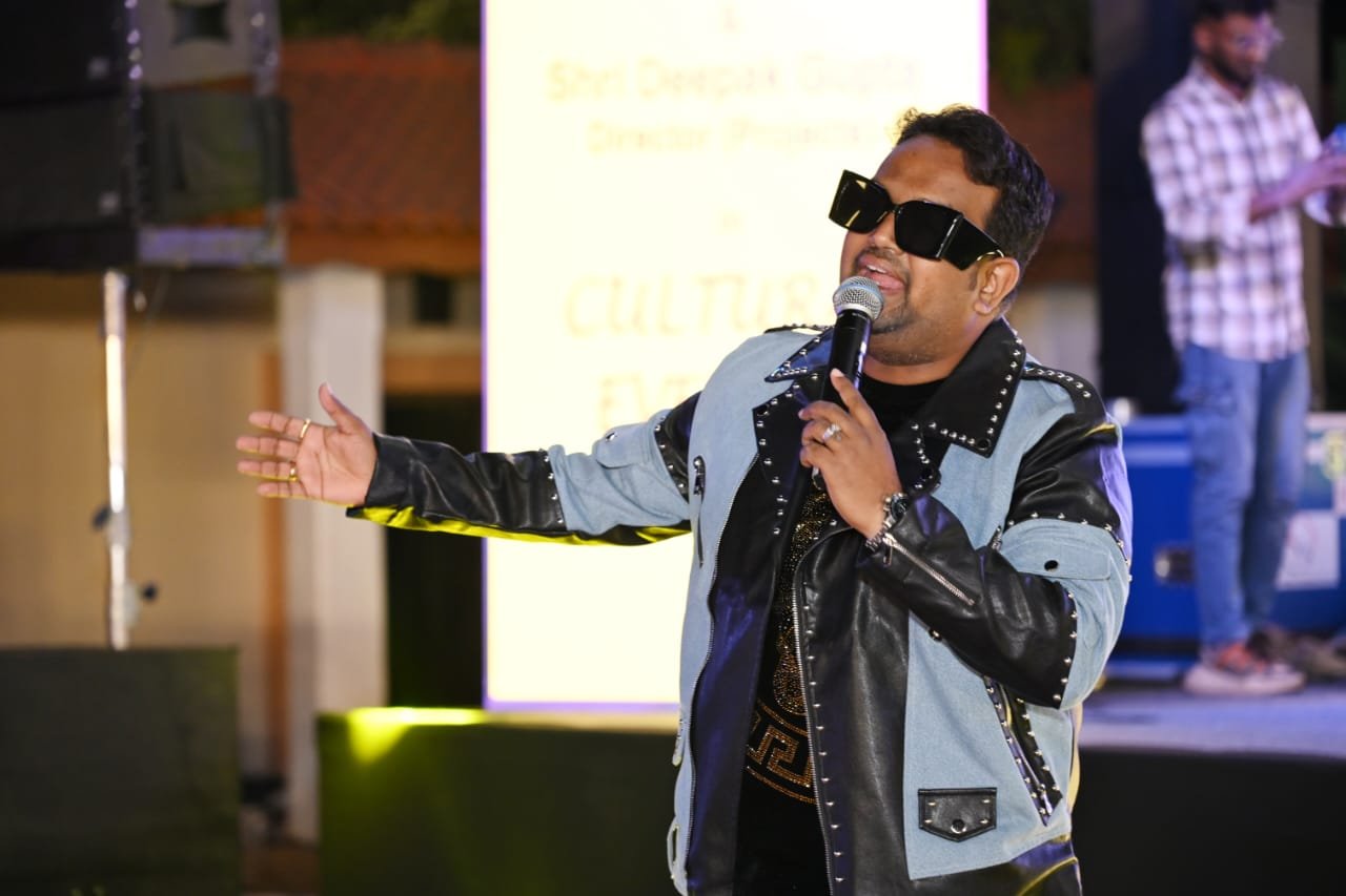 Vaibhav Pewal singing at a cultural event under open arms and stage lights